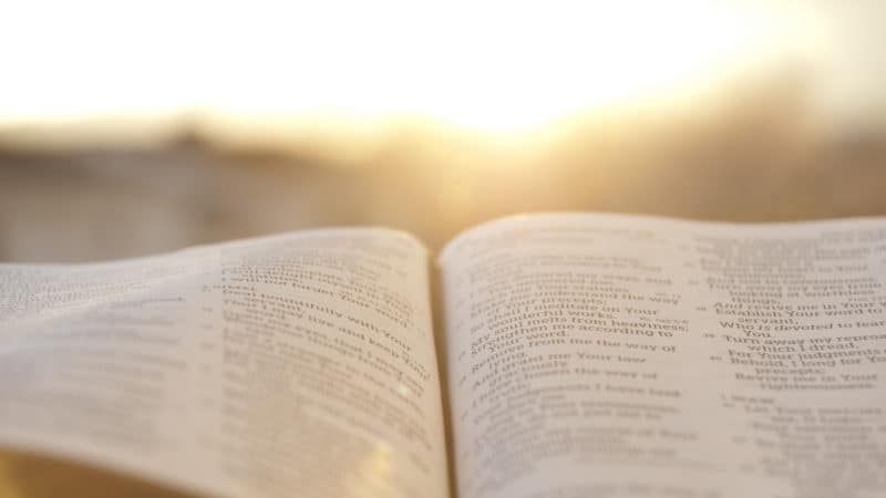 Open Bible with bright sunset in the background.